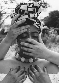Black and white portrait of woman with multiple hands in nature, conveying emotion.