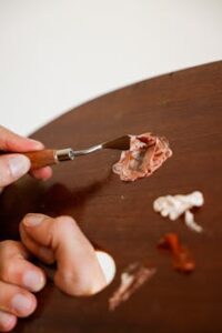 Detailed view of an artist mixing paint on a wooden palette using a spatula. Perfect for creative projects.