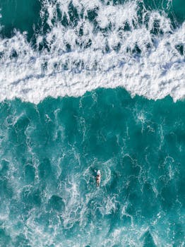 Stunning aerial shot of a lone surfer riding vibrant turquoise waves in Brazil's pristine waters.